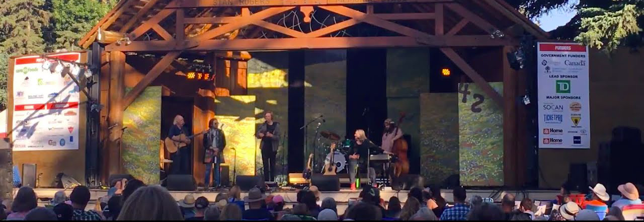 Image de Stéphane qui joue dans un concert avec le groupe de Connie Kaldor sur la scène principale du festival de musique folklorique Canmore. Photo de Anna Orton-Hatzis.